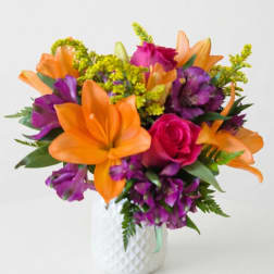 Orange lilies and purple flowers in a white vase with a pink rose