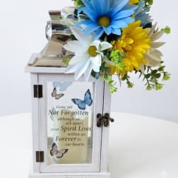 White memorial lantern with blue and yellow daisies and a remembrance message