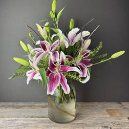 Pink and white lilies arranged in a glass vase