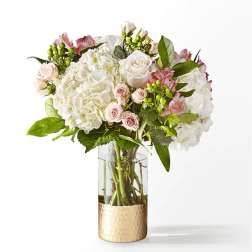 White and pink floral bouquet in a clear glass vase with a gold base