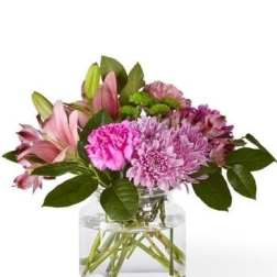 Pink lilies and purple flowers in a clear glass vase