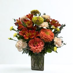 Mixed orange and cream flowers in a square glass vase