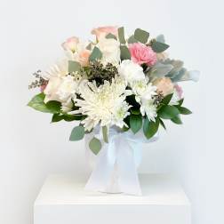 Bouquet of white and blush flowers in a white vase with a ribbon