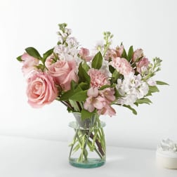 Pink roses and mixed pastel flowers in a clear glass vase