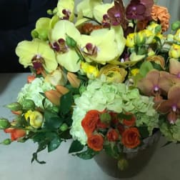 Mixed bouquet with orchids, hydrangeas, and roses in a dark vase