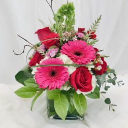 Pink gerbera daisies and red roses arranged in a glass vase