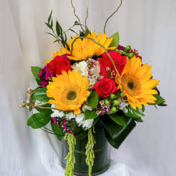 Bright bouquet of sunflowers and red roses in a glass vase