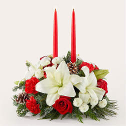 Holiday centerpiece with red candles, white lilies, and red roses