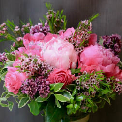 Pink peonies and roses arranged in a glass vase