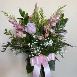 Pink and lavender bouquet in a glass vase with a pink ribbon