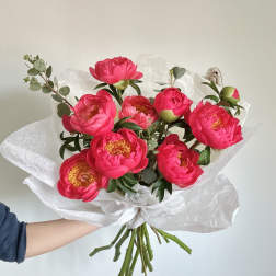 Bouquet of bright pink peonies wrapped in white paper
