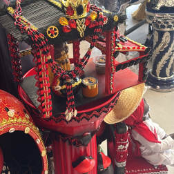 Decorative ceremonial display with red and black beaded adornments and a crown