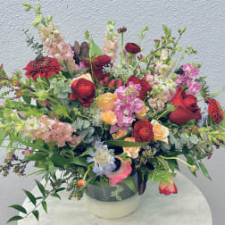 Large mixed bouquet in a round vase with red, pink, peach, and white flowers