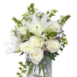 White roses and lilies arranged in a clear square vase