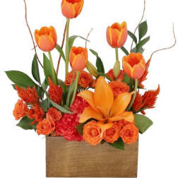 Orange tulips and roses arranged in a wooden box