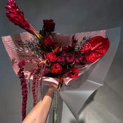 Red bouquet with anthurium, roses, and hanging blooms in pink wrap