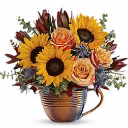 Sunflowers and peach roses arranged in a copper mug