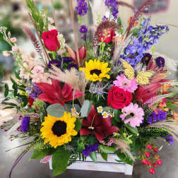 Colorful mixed bouquet with roses, lilies, sunflowers, and a butterfly accent