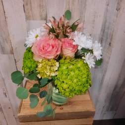 Pink roses with white daisies and green hydrangeas in a striped vase