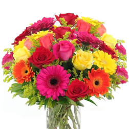 Colorful bouquet of roses and gerbera daisies in a clear glass vase