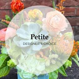 Mixed bouquet with pale hydrangea, ranunculus, and protea in a blue container