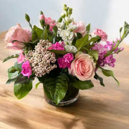 Pink and white mixed flower arrangement in a low glass vase