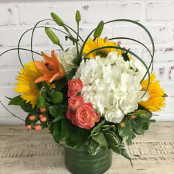 Bouquet of sunflowers, white hydrangea, pink roses, and orange lilies in a green vase