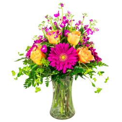 Bright mixed bouquet with orange roses and magenta daisies in a glass vase