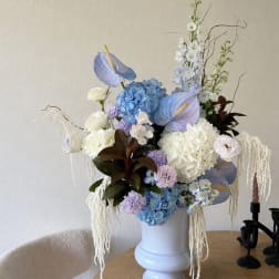 Large pastel floral arrangement in a white vase on a table
