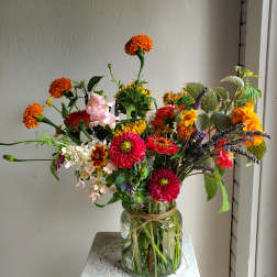 Mixed bouquet of bright flowers in a glass jar vase