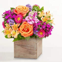 Mixed bouquet of orange roses and colorful flowers in a wooden box
