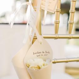 Cream wedding favor cones tied to a gold chair with white ribbon