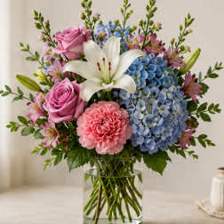 Bouquet of pink roses, blue hydrangeas, white lily, and pink carnations in a glass vase
