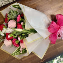 Bouquet of red and pink roses wrapped in white paper with a pink ribbon