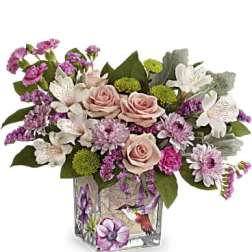 Pink and white floral arrangement in a decorated glass vase