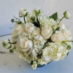 White roses and hydrangeas arranged in a low bowl vase