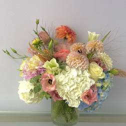 Pastel mixed flower arrangement in a textured glass vase