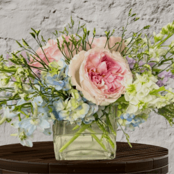 Pastel bouquet of pink and blue flowers in a clear glass vase