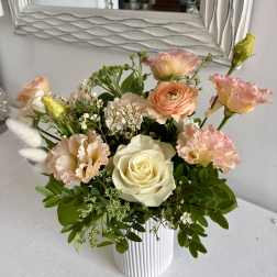 Mixed bouquet of cream roses and peach-pink blooms in a white ribbed vase