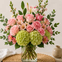 Pink roses and carnations with green hydrangeas in a glass vase