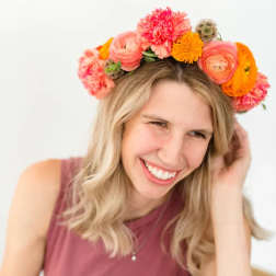 Woman wearing a colorful flower crown of pink, orange, and yellow blooms