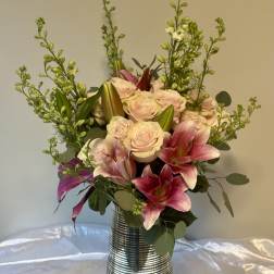 Pink lilies and pale roses arranged in a striped metal vase