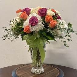 Bouquet of orange and magenta roses in a clear glass vase