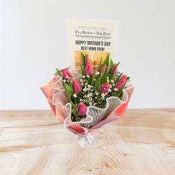 Small bouquet of pink tulips and white filler flowers with a Mother’s Day card in ruffled pink wrap.