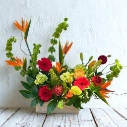 Mixed floral arrangement with orange bird-of-paradise and pink gerbera daisies in a wooden box