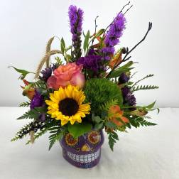 Colorful bouquet in a purple skull vase with a sunflower and purple blooms