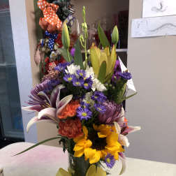 Mixed bouquet in a glass vase with a yellow ribbon