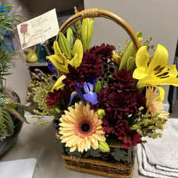 Basket arrangement with yellow lilies, burgundy mums, and peach gerbera daisies