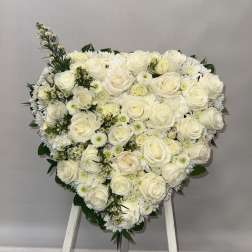 Heart-shaped arrangement of white roses and daisies on an easel