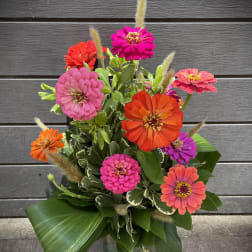 Bright zinnia bouquet in a glass vase with mixed pink, orange, and purple blooms